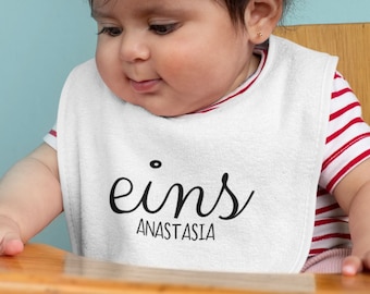 Personalisiertes 'Eins' Baby Lätzchen, Bio-Baumwollqualität, Weißes Kinderlatz mit Namenszug, Erster Geburtstag, Unverwechselbare Babymode