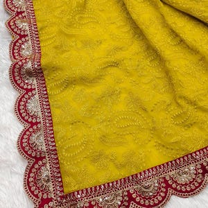 Pu&ograve; includere: Un sari di chiffon giallo con un bordo ricamato rosso e oro. Il bordo ha un bordo a festoni e presenta paillettes e perline.