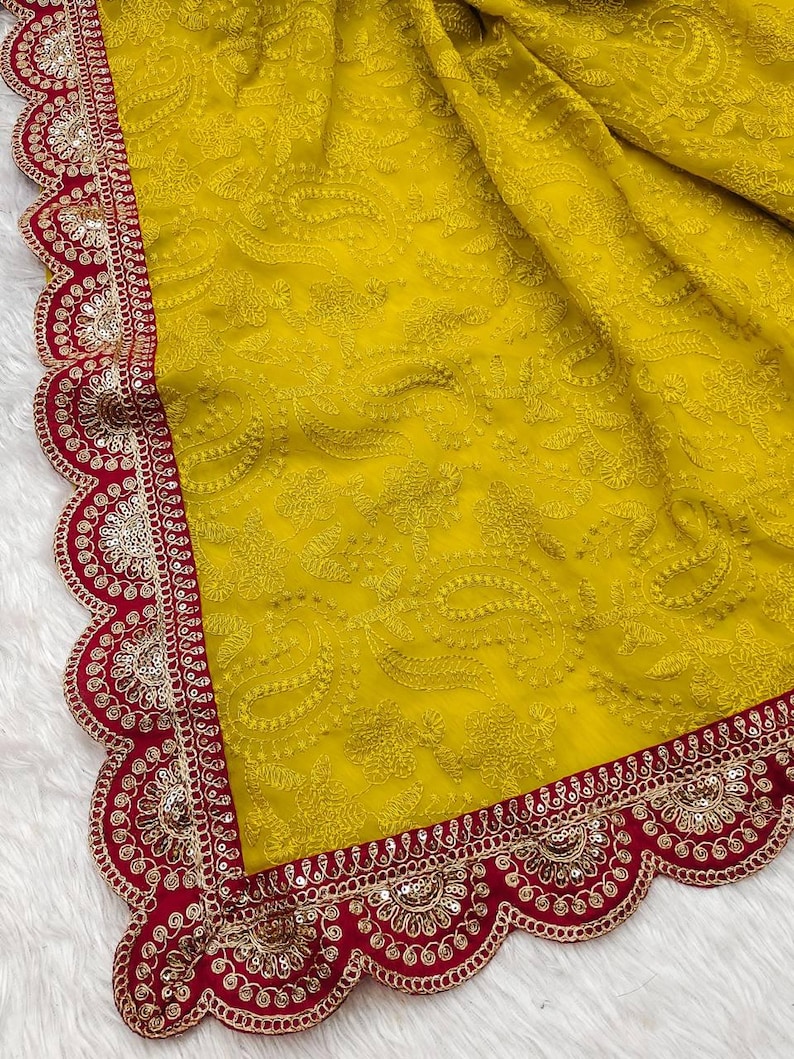 Pu&ograve; includere: Un sari di chiffon giallo con un bordo ricamato rosso e oro. Il bordo ha un bordo a festoni e presenta paillettes e perline.