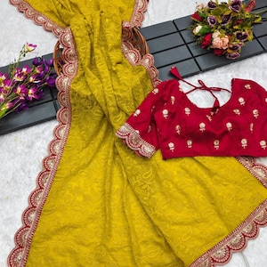 Pu&ograve; includere: Un sari giallo con un bordo ricamato in rosso e oro. Il sari presenta un motivo paisley ed &egrave; realizzato in un tessuto morbido e fluido. &Egrave; inclusa una blusa rossa con ricami dorati.