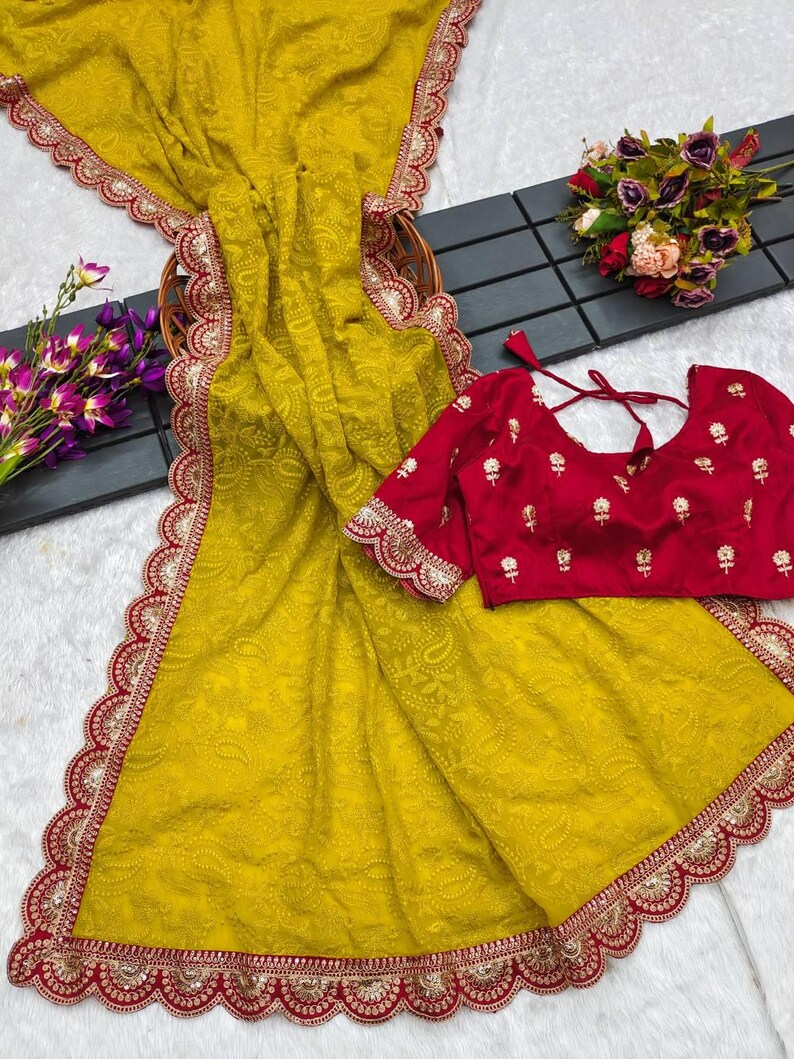 Pu&ograve; includere: Un sari giallo con un bordo ricamato in rosso e oro. Il sari presenta un motivo paisley ed &egrave; realizzato in un tessuto morbido e fluido. &Egrave; inclusa una blusa rossa con ricami dorati.