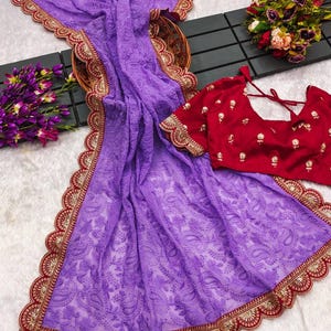 Pu&ograve; includere: Un sari di chiffon viola con un bordo ricamato in rosso e oro. Il sari presenta un delicato motivo floreale ed &egrave; perfetto per un'occasione speciale.