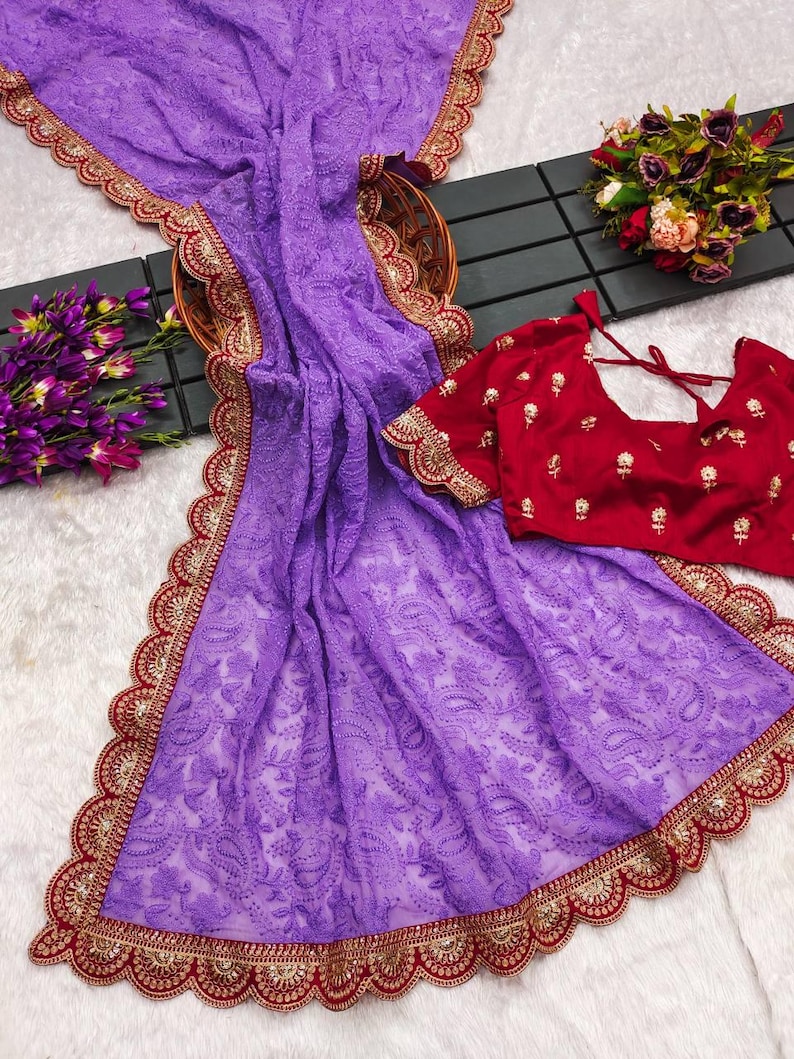 Pu&ograve; includere: Un sari di chiffon viola con un bordo ricamato in rosso e oro. Il sari presenta un delicato motivo floreale ed &egrave; perfetto per un'occasione speciale.