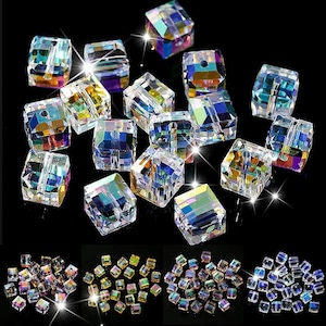 May include: A collection of iridescent, faceted, square glass beads. The beads are various shades of blue, green, and purple. The beads are arranged in a random pattern on a black background.