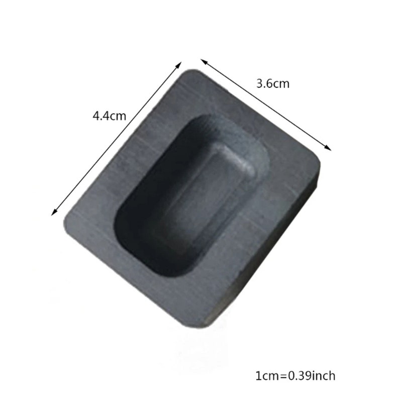 Puede incluir: Un molde de grafito negro para fundir barras de metal. El molde es rectangular con una cavidad rectangular en el centro. El molde mide 4,4 cm por 3,6 cm.