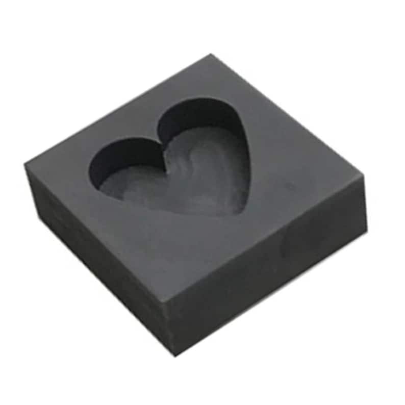 Puede incluir: Un molde cuadrado gris con un recorte en forma de coraz&oacute;n. El molde est&aacute; hecho de un material que parece goma o silicona.