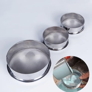 May include: Three stainless steel mesh sieves of different sizes. The sieves are round and have a smooth, shiny finish. The largest sieve is in the background, and the smallest sieve is in the foreground. The sieves are used for separating materials of different sizes.