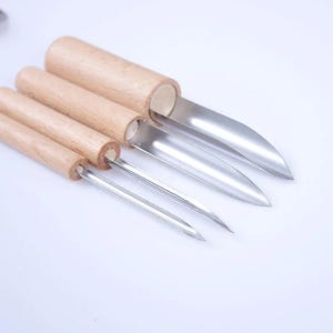 May include: Set of four stainless steel and wood kitchen tools. The tools have wooden handles and stainless steel blades. The blades are different shapes and sizes, designed for various kitchen tasks.