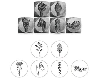 May include: Set of six metal stamps featuring floral designs. The stamps are square and have a raised design. The designs include a thistle, a snowdrop, a sprig of leaves, a leaf, a sprig of flowers, and a branch of flowers.