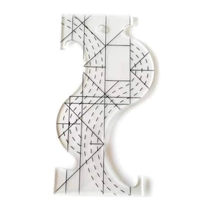 Puede incluir: Una regla de acolchado de plástico transparente con forma curva y un patrón de cuadrícula. La regla tiene dos recortes en los lados.