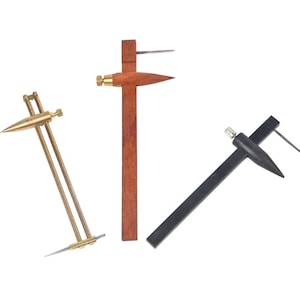 May include: Three different types of drafting tools. The first is a brass compass with a pointed tip. The second is a wooden compass with a pointed tip. The third is a black compass with a pointed tip.