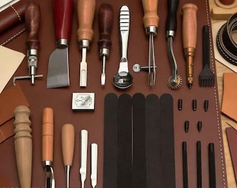 May include: A collection of leatherworking tools, including knives, awls, edge creasers, and a stitching groover, arranged on a brown leather surface. The tools have wooden handles and metal blades, with various shapes and sizes for different leathercrafting tasks.
