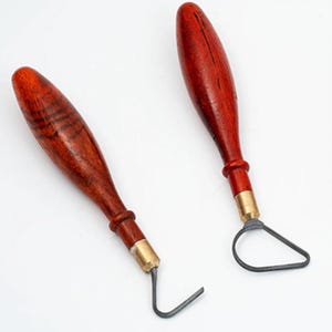 May include: Two pottery loop tools with wooden handles and metal loops. The handles are a rich, dark brown with visible wood grain. The metal loops are a dark gray color. These tools are used for sculpting and trimming clay.
