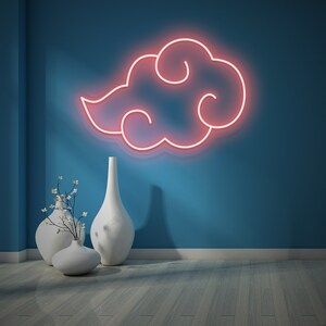 May include: A pink neon sign in the shape of a cloud with a swirling design, hanging on a blue wall. Two white ceramic vases with white flowers are in the foreground.