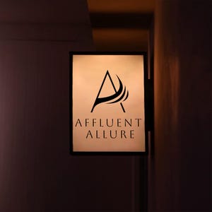 Op de afbeelding: Rechthoekig verlicht bord met de tekst "AFFLUENT ALLURE" in een schreefletter. Het bord heeft een gestileerde zwarte "A" met gebogen lijnen. Het bord is bevestigd aan een donkere muur.