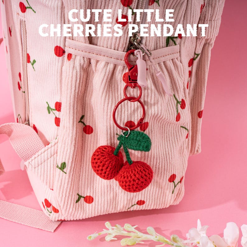 May include: A pink corduroy backpack with a cherry print and a cute little cherry pendant. The pendant is made of red yarn and has green leaves.