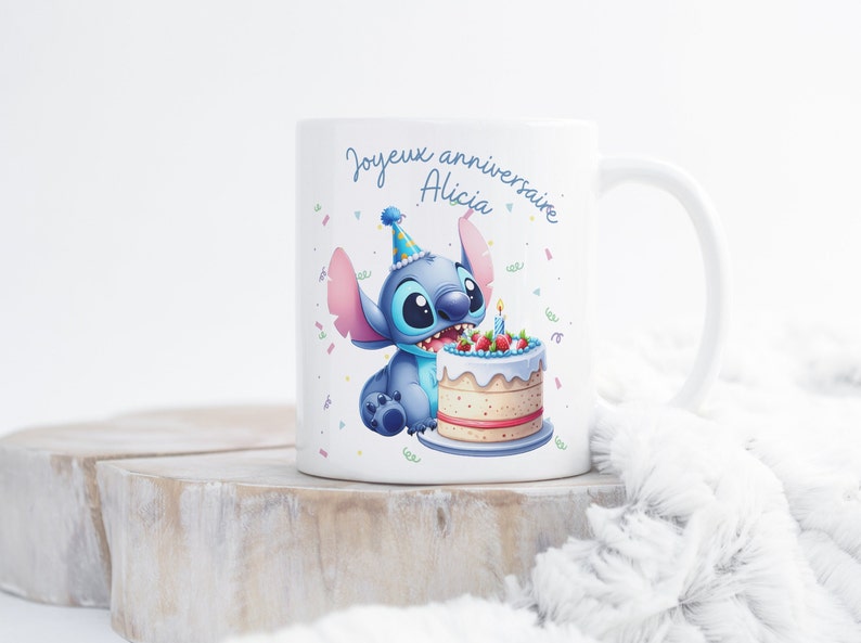 May include: White ceramic mug with a blue Stitch character wearing a party hat and holding a birthday cake with a lit candle. The mug says "Joyeux anniversaire Alicia".