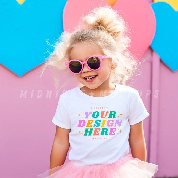 Children's White T-Shirt Mockup - Little Girl with Pink Sunglasses and Tutu in Front of a Heart Wall