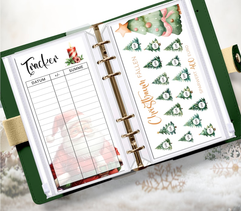 May include: A white planner with a green cover and gold rings. The planner has a page with a Christmas tree savings tracker and a page with a Christmas tracker for recording dates and amounts. The Christmas tree savings tracker has a watercolor illustration of a Christmas tree with ornaments and a star on top. The Christmas tracker page has a watercolor illustration of Santa Claus.