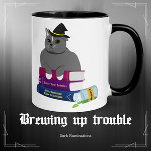 May include: White ceramic mug with a black interior and handle. The mug features a gray cat wearing a witch hat, sitting on books with the titles "Curse Your Enemies" and "World Domination." The mug also has the text "Brewing up trouble" and "Dark Ruminations."