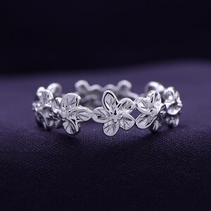 May include: A silver ring with a floral design. The ring is made of a series of small flowers that are connected together.