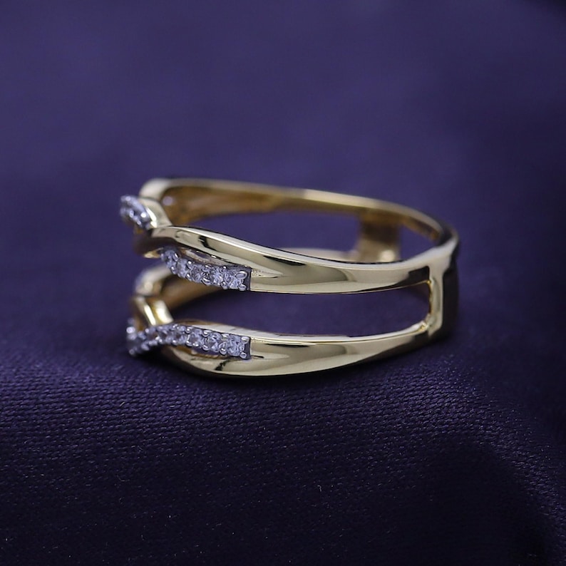 Op de afbeelding: Een gouden ring met twee banden die in elkaar zijn gevlochten en bezet zijn met kleine diamanten.