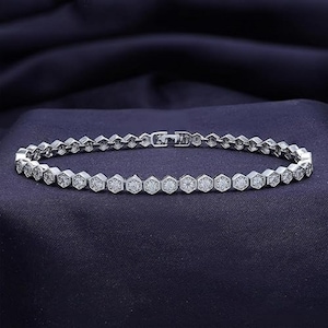 May include: A silver bracelet featuring a row of hexagonal-shaped stones set with small clear cubic zirconia. The bracelet has a polished finish.
