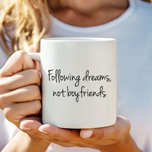 May include: White ceramic mug with black text that reads "Following dreams, not boyfriends".
