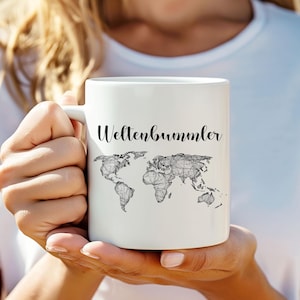 Könnte beinhalten: Weiße Keramiktasse mit einer schwarzen Umrandung einer Weltkarte und dem Text "Weltenbummler" in Schwarz.