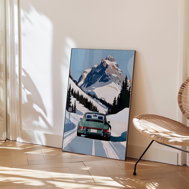 May include: A vintage green Porsche 911 driving on a snowy mountain road. The car is driving towards a snow-capped mountain peak in the background. The road is lined with trees on either side.
