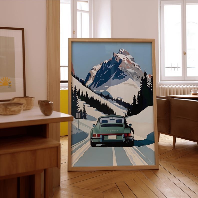 May include: A framed poster featuring a vintage green Porsche driving on a snowy mountain road. The poster has a blue sky and white snow-capped mountains in the background.