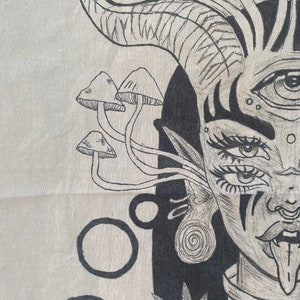 Puede incluir: Dibujo en blanco y negro de una mujer con un tercer ojo, cuernos y la lengua fuera. Lleva un pendiente en espiral y una hoja de marihuana detr&aacute;s de ella. Hay setas en la esquina superior izquierda de la imagen.