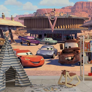 K&ouml;nnte beinhalten: Ein farbenfrohes Wandbild zum Thema Cars mit Lightning McQueen, Mater und anderen Figuren aus dem Film. Das Wandbild zeigt eine Tankstelle mit einem Schild, auf dem "Flo's V8 Cafe" steht.