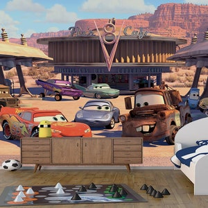 K&ouml;nnte beinhalten: Ein farbenfrohes Wandbild zum Thema Cars mit verschiedenen Cartoon-Autos, darunter Mater, Lightning McQueen und ein blaues Auto mit rotem Streifen. Das Wandbild ist vor dem Hintergrund einer W&uuml;stenlandschaft mit einer Tankstelle und einem Schild mit der Aufschrift "Flo's V8 Cafe" platziert.
