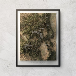 May include: A framed topographic map print titled COLORADO FOURTEENERS, featuring a detailed aerial view of mountainous terrain in shades of green, brown, and tan, with small white text labels marking specific peaks across the landscape.
