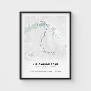 May include: Framed print of Kit Carson Peak in Sangre de Cristo, Colorado. The artwork features a detailed outline of the mountain's shape, with text indicating the peak's name, location, and elevation of 14,147 ft. The print includes the Willow Lake & Challenger Point.