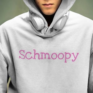 May include: A white hooded sweatshirt with a pink graphic that says "Schmoopy".