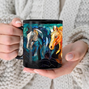 May include: Black coffee mug with a stained glass design of three horses' heads. The horses are in shades of blue, yellow, and orange.