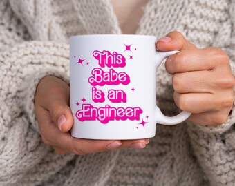 May include: White ceramic mug with pink text that reads "This Babe is an Engineer" with pink stars around the text.