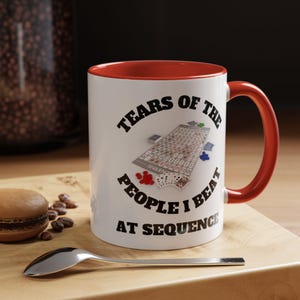 May include: White ceramic coffee mug with a red rim and handle. The mug features a black graphic of a Sequence game board with the text "Tears of the People I Beat at Sequence".