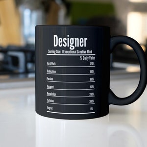 May include: Black ceramic coffee mug with the word "Designer" and a list of qualities and their daily value percentages. The qualities include hard work, dedication, passion, respect, knowledge, caffeine, and regret.