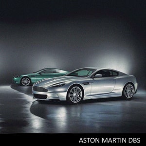 May include: Two Aston Martin DBS sports cars, one silver and one green, are shown on a dark background. The green car is a racing version with a large wing and a number "000" on the side. The text "ASTON MARTIN DBS" is displayed at the bottom of the image.