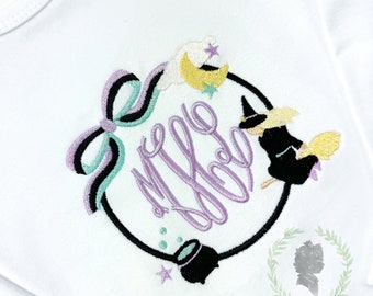 May include: A white onesie with a purple and black embroidered design. The design features a witch flying on a broomstick, a cauldron, stars, and a moon. The text "My Boo" is written in a purple cursive font.