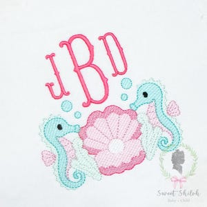 May include: Embroidered design with a pink monogram (JBI), turquoise seahorses, a pink seashell, and bubbles on a white background. The text "Sweet Shiloh Baby + Child" is also visible. The design is suitable for baby items.