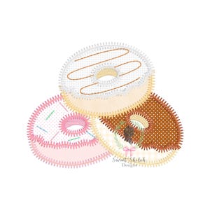 Könnte beinhalten: Drei gestickte Donuts, einer mit weißem Zuckerguss und Streuseln, einer mit rosa Zuckerguss und Streuseln und einer mit braunem Zuckerguss und Streuseln.