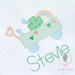 Puede incluir: Diseño bordado con un carro verde con un arcoíris, un trébol y banderines. El nombre "Stevie" está bordado en verde. El diseño incluye una pala y una regadera azul.