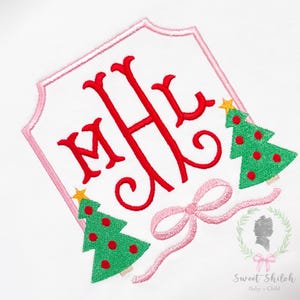 May include: White decorative emblem with a pink border, featuring a red monogram and two green Christmas trees with red ornaments. A pink bow and a gold star adorn the design, perfect for holiday-themed baby and child products.