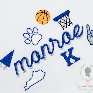May include: Embroidered design featuring a basketball, hoop, paw print, and a foam finger. The name "Monroe" is displayed in blue script with a shadow effect, along with a blue "K" and a Kentucky outline. The design is on a white background.