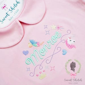 May include: A light pink baby outfit with a Peter Pan collar. The outfit is embroidered with the name "Monroe" in a cursive font, along with a unicorn, fairy, stars, hearts, and a crown. The text "Sweet Shiloh Baby + Child" is also visible.