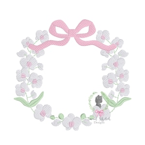 Puede incluir: Corona floral bordada con orquídeas blancas con centros rosas y hojas verdes. Un lazo rosa está en la parte superior. El diseño incluye el texto "Sweet Shiloh Designs" en la parte inferior.